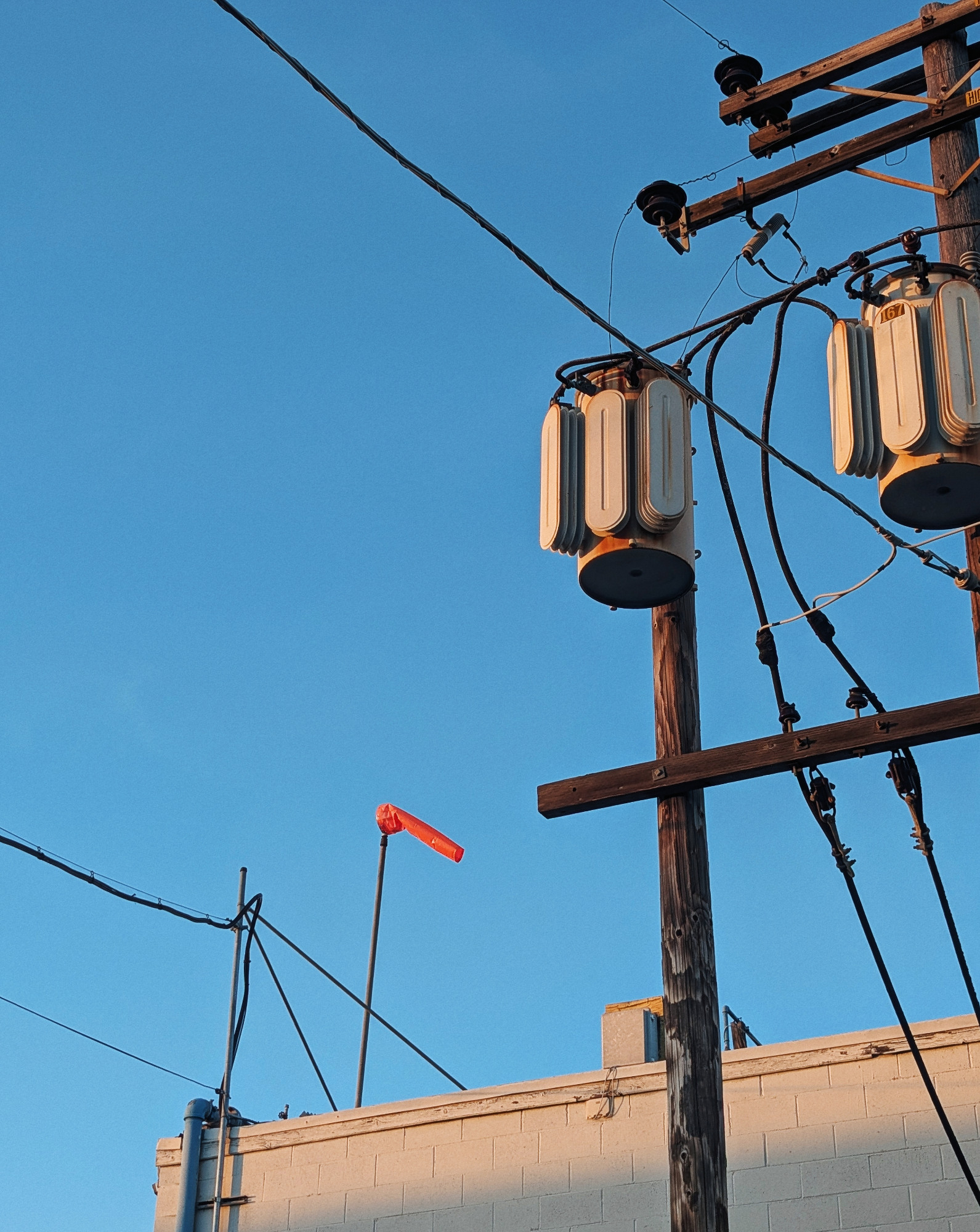 Red flag against bluesky framed between power wires