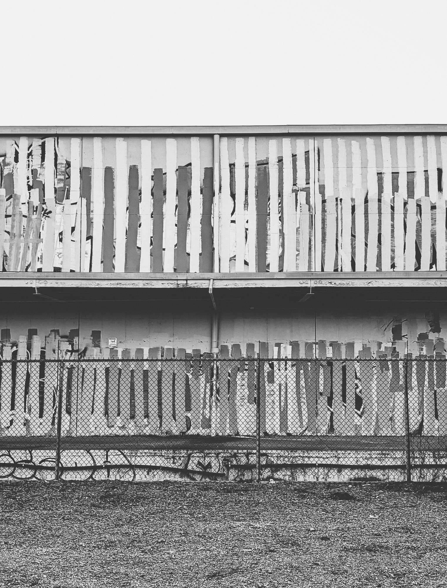Black and white photograph of a lazy graffiti buffer who paints in stripes. The photo is split horizontally so the sky building and ground are even in the conposition